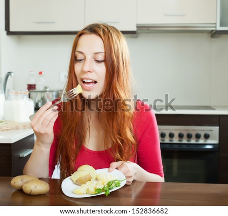 Casual long-haired girl eating potatoes at home interior
