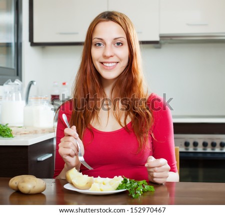 Happy  woman in red eating jacket potatoes at home interior