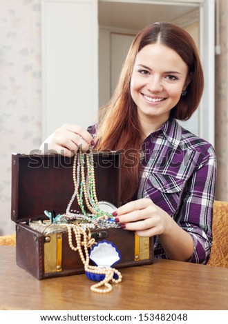 portrait of happy girl chooses jewelry in treasure chest