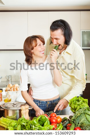 happy couple with fresh vegetables and greens in home kitchen