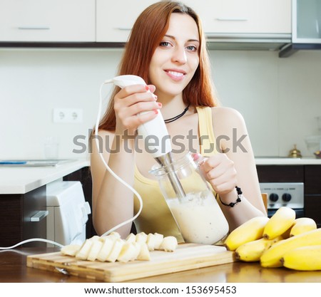cheerful woman  making milk shake with bananas at home