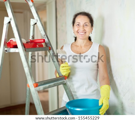 Mature woman makes repairs in the apartment