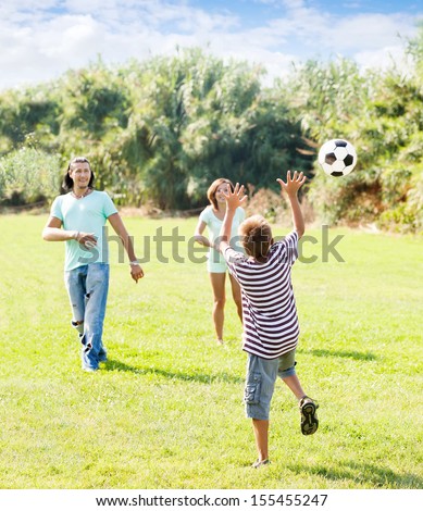 teenage boy and happy parents playing in soccer at summer park