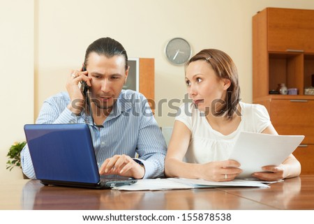 serious middle-aged man and woman looking financial document