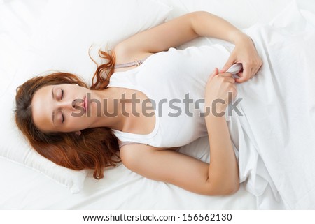 Red-haired woman sleeping on a fluffy pillow in bed at home