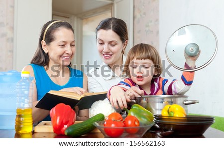 Happy women of three generations cook vegetables in the kitchen at home