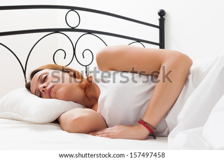 Red-haired woman is sleeping on a white pillow in bed at home