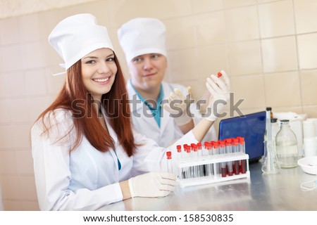 Positive nurse and male doctor works with test tubes in clinic lab