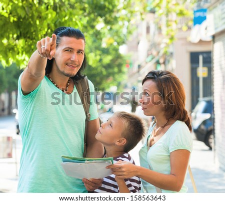 Middle-aged man pointing the direction for family at city street