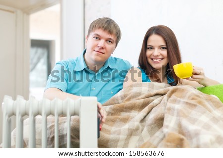 Couple  relaxing at home near oil heater