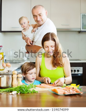 Happy family of four cooking red fish at home
