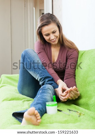 Happy beauty woman looks at her toenails at home