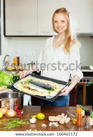 Ordinary woman cooking fish with potato in sheet pan