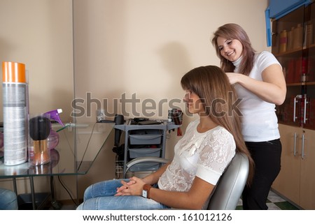 Female hair stylist works on woman hair in salon