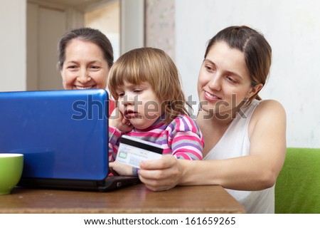 Two women and child  buying online with laptop and credit card  in living room