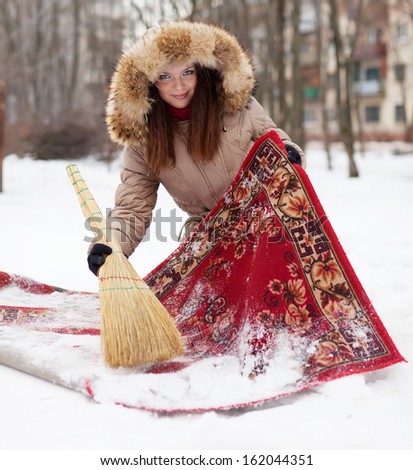 Smiling woman cleans red carpet with snow