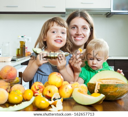 Happy family eating melon and other fruits over  table at home interior