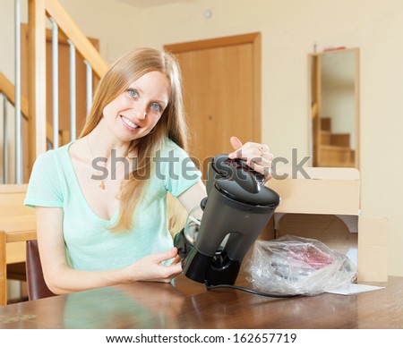 Happy woman reading  warranty card for new coffee machine  at home interior