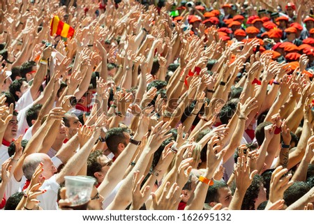 PAMPLONA, SPAIN - JULY 6: Start of San Fermin festival in July 6, 2013 in Pamplona, Spain. People raise their hands as a sign of beginning of the festival