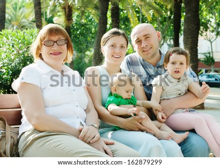 Portrait of happy three generations family sitting at summer park in sunny summer day