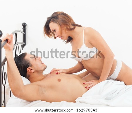 Middle-aged man with wife kissing and playing in bed at home