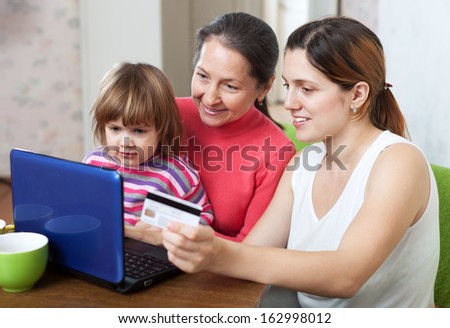 Family of three generations doing shopping in internet with credit card at home