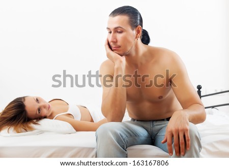 Unhappy man has problem near wife in bed