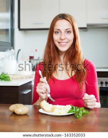 woman in red eating jacket potatoes at home interior