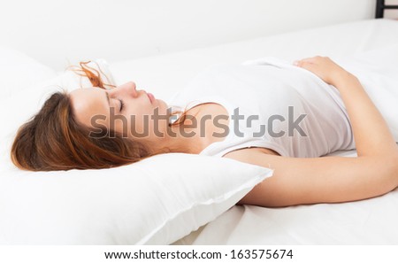 Pretty beautiful woman in shirt sleeping on white pillow in bed at home