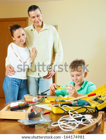 boy doing something with working tools, parents are watching in home