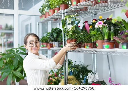 Happy mature woman chooses Stephanotis at flower store