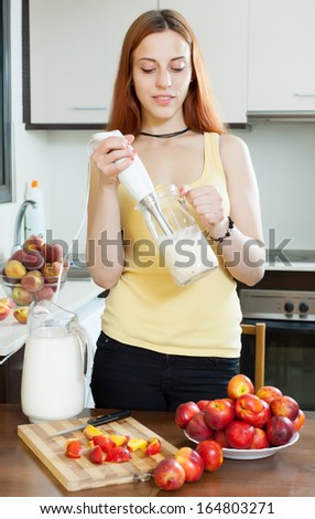 woman cooking dairy beverages with  blender from nectarines at  kitchen