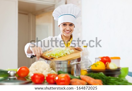 A happy chef works with vegetables in a commercial kitchen.