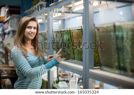 Woman chooses  fish in aquariums at pet-shop