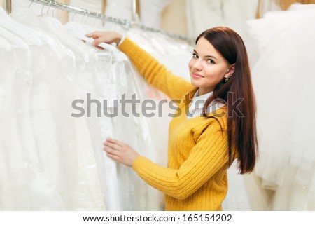 pretty bride chooses bridal gown in wedding salon