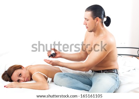 Man  massaging back of his wife in bedroom interior
