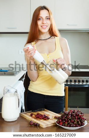 woman cooking dairy beverages with  blender from cherry at home kitchen