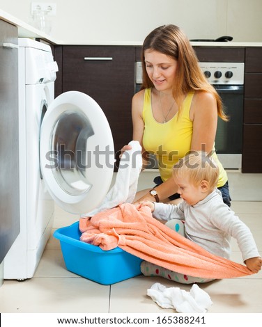 Family woman putting clothes in to washing machine   at home