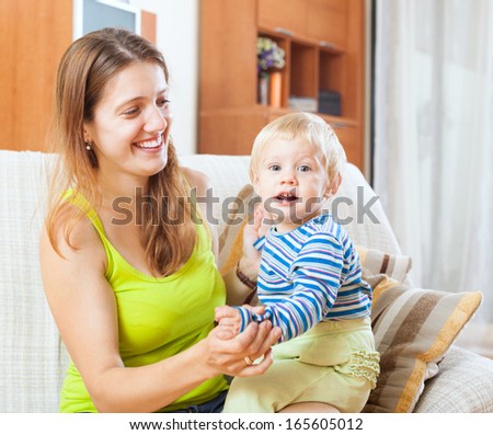 Portrait of happy mom and child on sofa in home interior