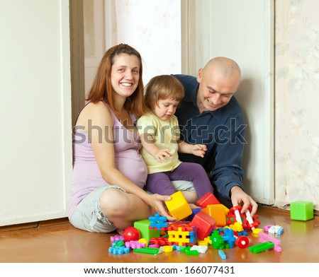 Happy parents plays with child in home interior
