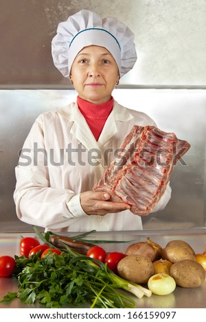 Cook woman with meat and vegetables in kitchen