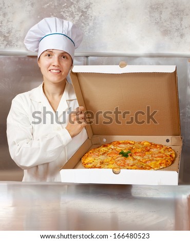 female cook with fresh  pizza in box at kitchen