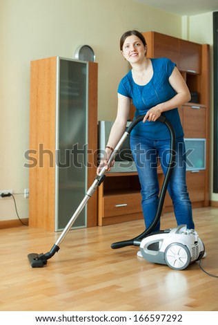 Woman cleans with vacuum cleaner on parquet floor