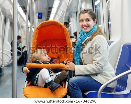 Smiling woman with child in stroller at subway train