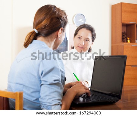 Smiling mature woman questionnaire for  social worker or employee of the company at table