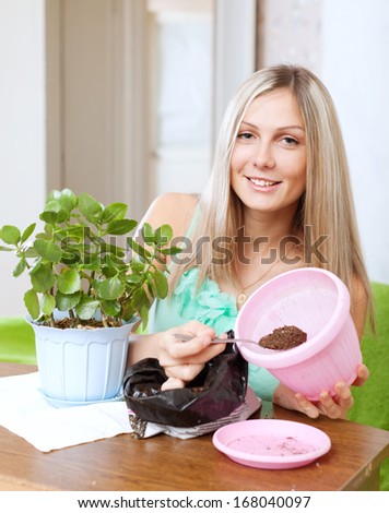 Young woman works with  flower pots at her home