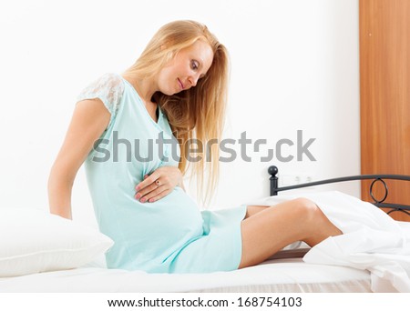 Sitting long-haired pregnancy woman in nightdress