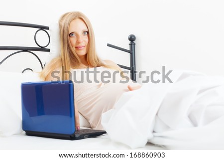 pregnancy woman awaking  with laptop on white sheet in her bed at home
