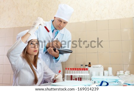 nurse and male doctor works with test tubes in clinic lab