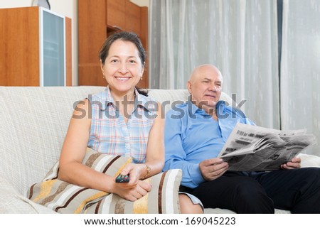 Portrait of happy family at home on the couch with the newspaper